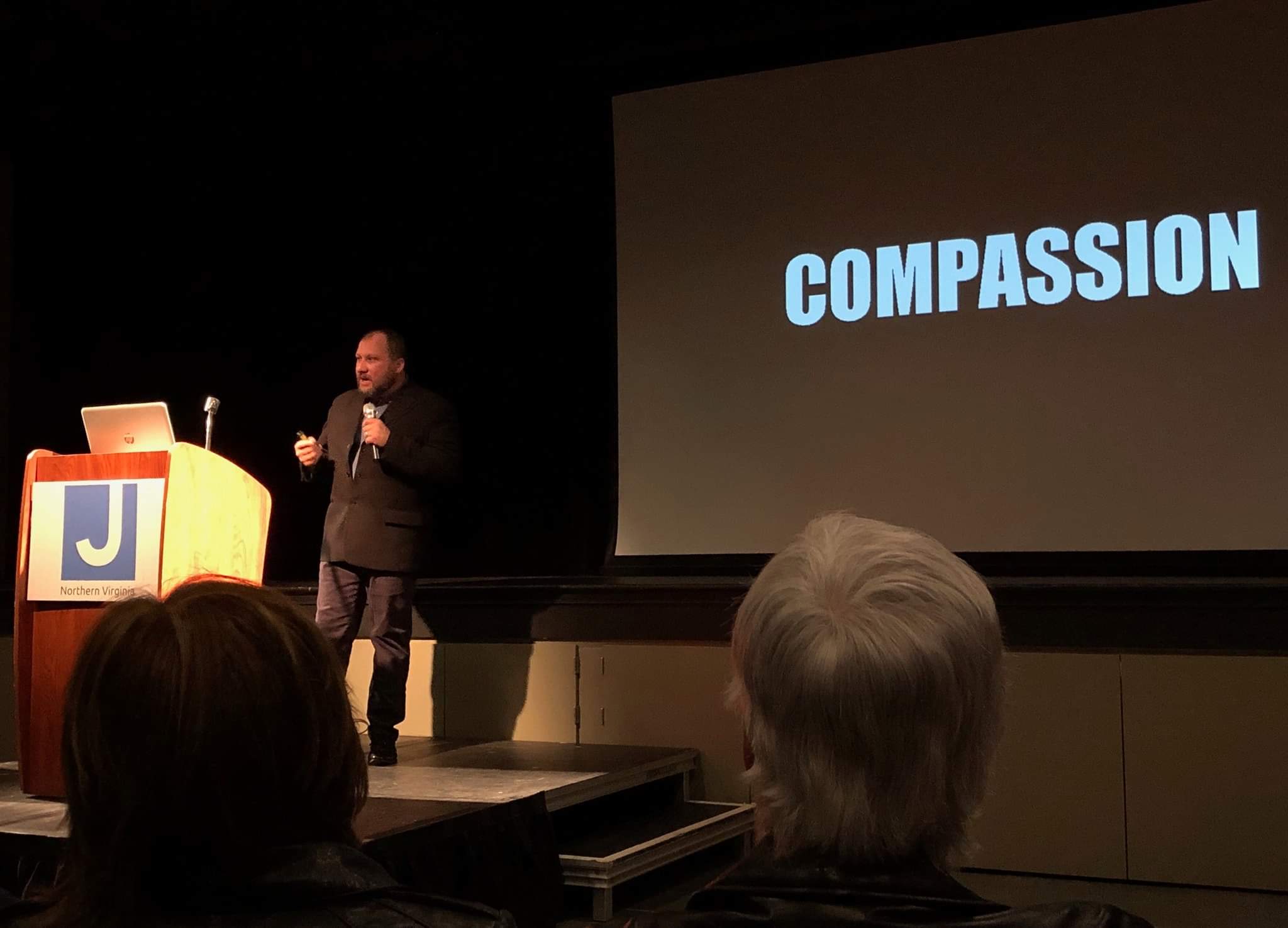 TM Garret speaking beside a compassion presentation slide