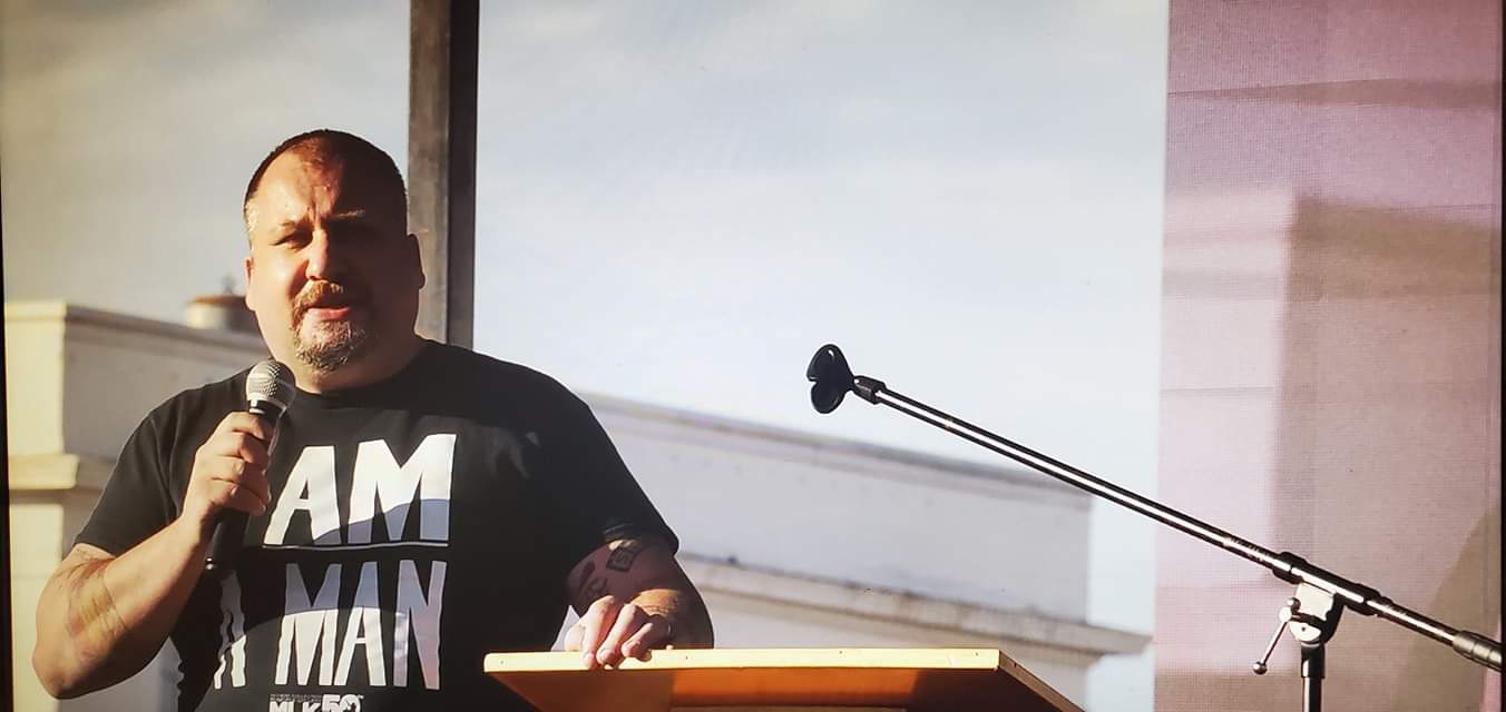 TM Garret speaking outdoors at a podium